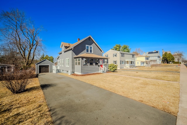 view of front of property featuring an outbuilding, a chimney, aphalt driveway, and a garage