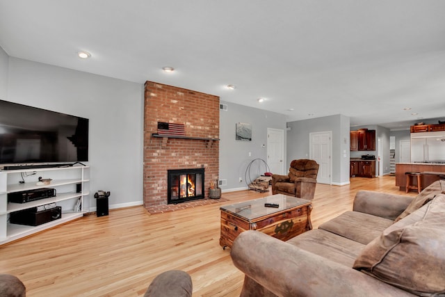 living room with recessed lighting, light wood-style flooring, a brick fireplace, and baseboards