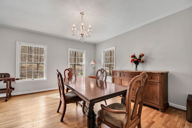 dining area with baseboards, visible vents, light wood-style floors, crown molding, and a notable chandelier