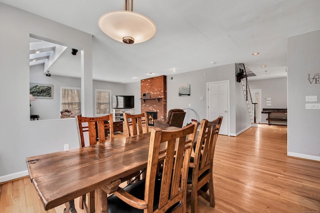 dining space featuring light wood finished floors, baseboards, stairs, recessed lighting, and a fireplace