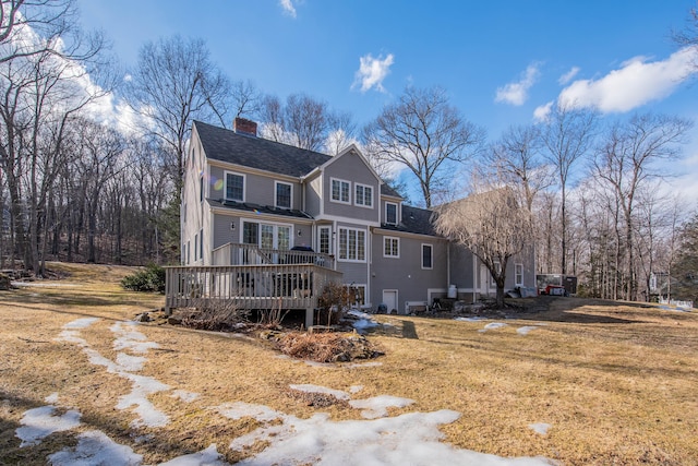 view of front of property with a wooden deck, a chimney, and a shingled roof