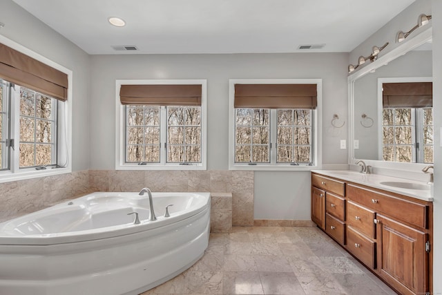 bathroom featuring double vanity, a bath, visible vents, and a sink