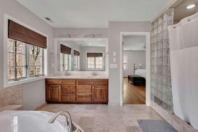 bathroom featuring a sink, visible vents, ensuite bathroom, and a washtub