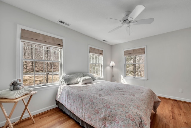 bedroom featuring light wood-type flooring, visible vents, multiple windows, and baseboards