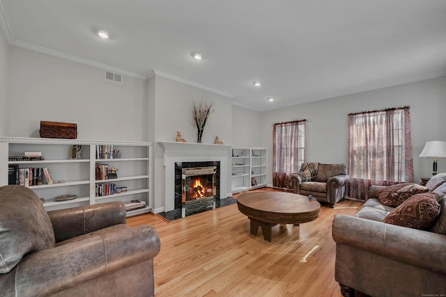 living room featuring visible vents, a fireplace, recessed lighting, ornamental molding, and light wood-style floors