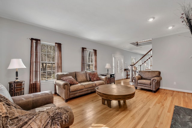 living area featuring light wood-type flooring, stairs, baseboards, and ornamental molding