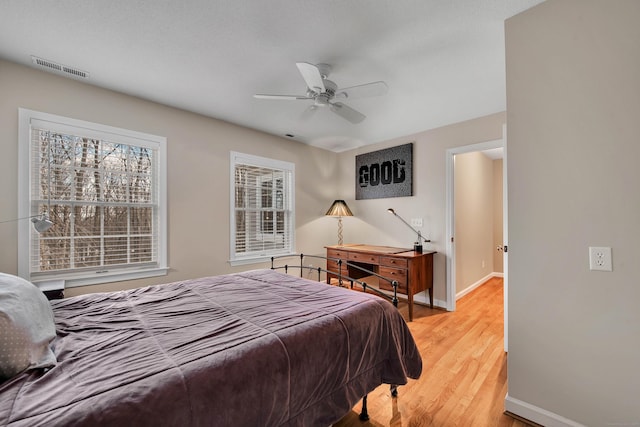 bedroom featuring light wood-type flooring, baseboards, visible vents, and ceiling fan