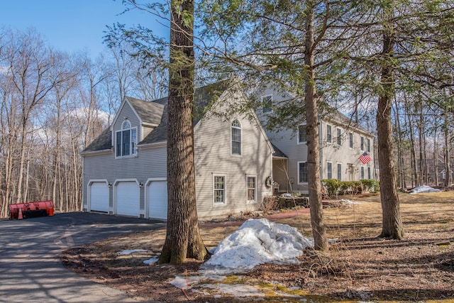 view of property exterior featuring aphalt driveway, a garage, and roof with shingles