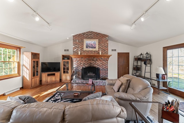 living area with a baseboard radiator, plenty of natural light, wood finished floors, and vaulted ceiling