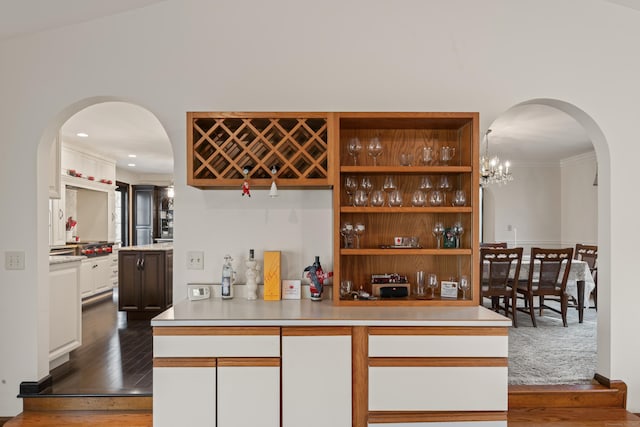 bar featuring dark wood-type flooring, arched walkways, and ornamental molding