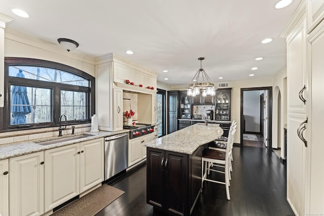 kitchen featuring tasteful backsplash, dark wood-style floors, appliances with stainless steel finishes, arched walkways, and a sink