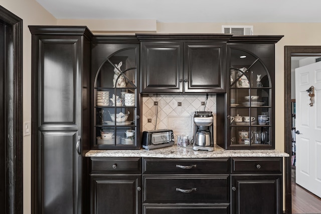 bar featuring visible vents, backsplash, wood finished floors, and a toaster