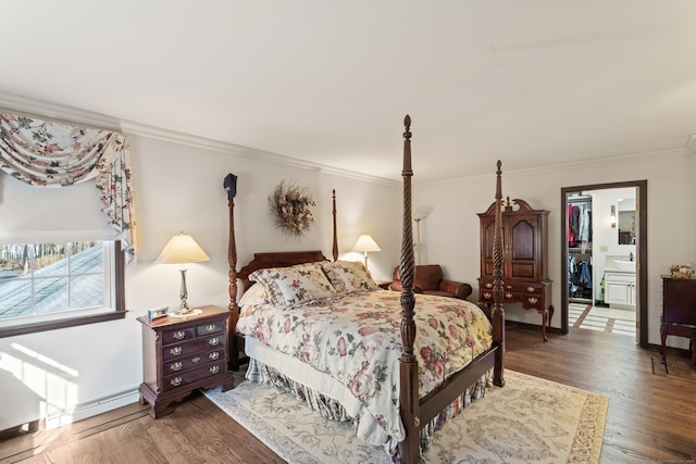 bedroom featuring a closet, wood finished floors, a walk in closet, and ornamental molding