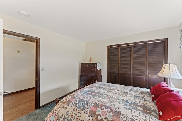 bedroom featuring a closet, baseboards, attic access, and wood finished floors