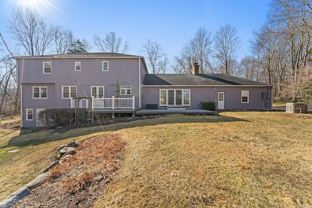 back of house featuring a deck, a chimney, and a yard