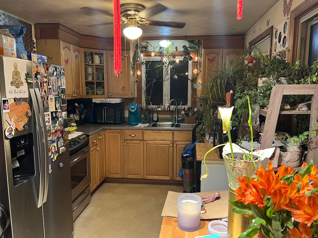 kitchen with stainless steel appliances, a sink, a ceiling fan, light floors, and glass insert cabinets