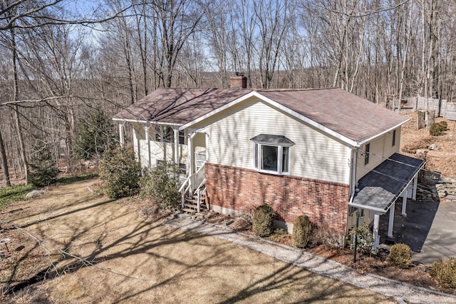 view of property exterior with stairway, a porch, a shingled roof, a chimney, and brick siding