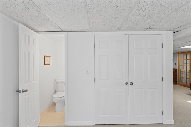 bathroom featuring tile patterned flooring, toilet, and a paneled ceiling