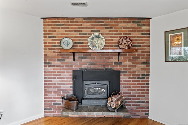 interior details with visible vents, a wood stove, baseboards, and wood finished floors