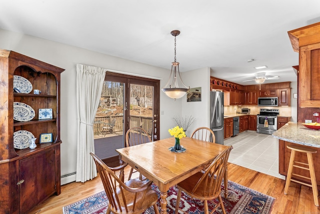 dining area featuring a baseboard heating unit, ceiling fan, and light wood finished floors