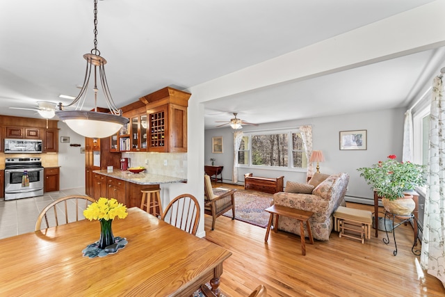 dining space with ceiling fan, light wood-style floors, and a baseboard radiator