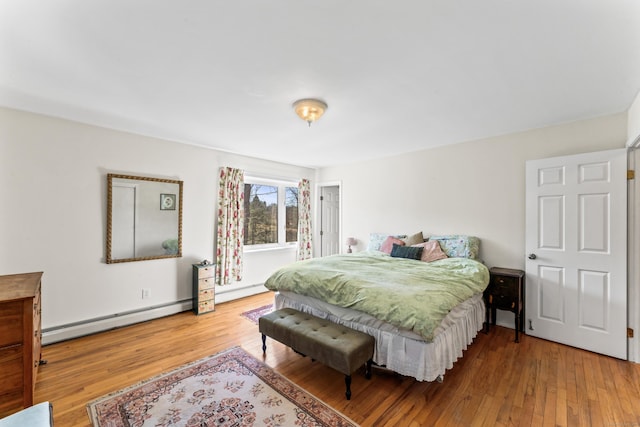 bedroom with a baseboard heating unit, baseboard heating, and hardwood / wood-style floors