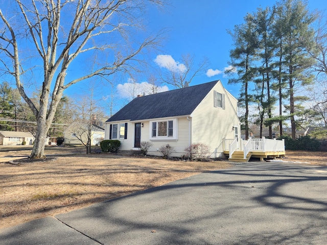 cape cod-style house with a shingled roof and a wooden deck