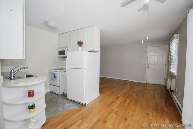 kitchen featuring a sink, white appliances, light wood-style floors, and white cabinetry