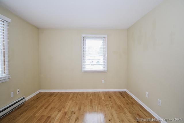 unfurnished room featuring light wood-style floors, baseboards, and a baseboard radiator