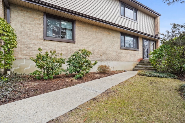 view of side of home featuring brick siding and a yard