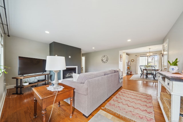 living room featuring a notable chandelier, recessed lighting, a fireplace, wood finished floors, and baseboards