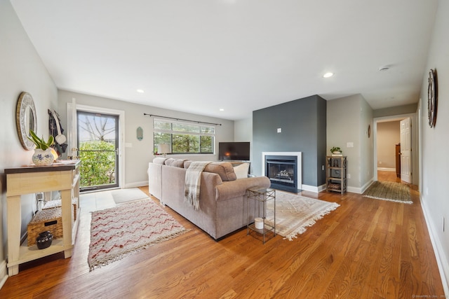 living area with a fireplace with flush hearth, recessed lighting, baseboards, and wood finished floors