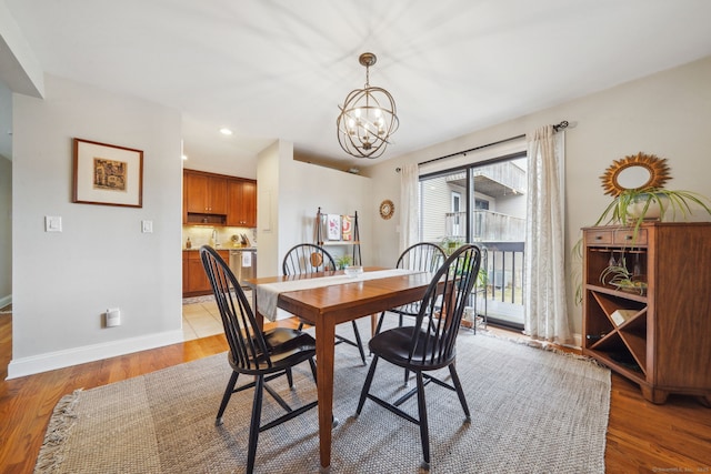 dining space with light wood-type flooring, baseboards, a notable chandelier, and recessed lighting