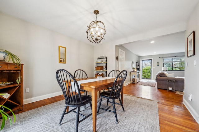 dining room with baseboards, a notable chandelier, and light wood finished floors