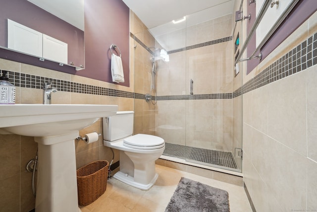 full bath featuring toilet, a stall shower, tile patterned flooring, and tile walls