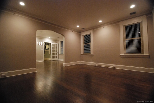 spare room with arched walkways, recessed lighting, crown molding, and wood finished floors