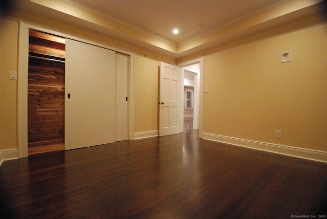 unfurnished bedroom with baseboards, dark wood finished floors, recessed lighting, a closet, and a raised ceiling