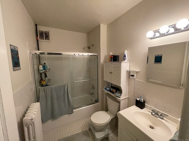 full bath featuring tile patterned floors, visible vents, combined bath / shower with glass door, radiator, and tile walls