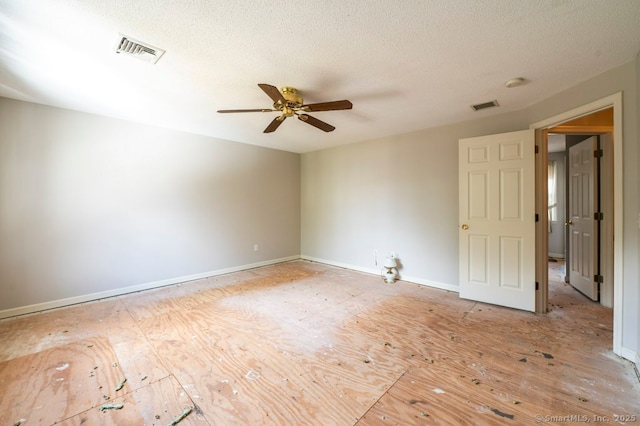 empty room featuring a textured ceiling, baseboards, visible vents, and a ceiling fan