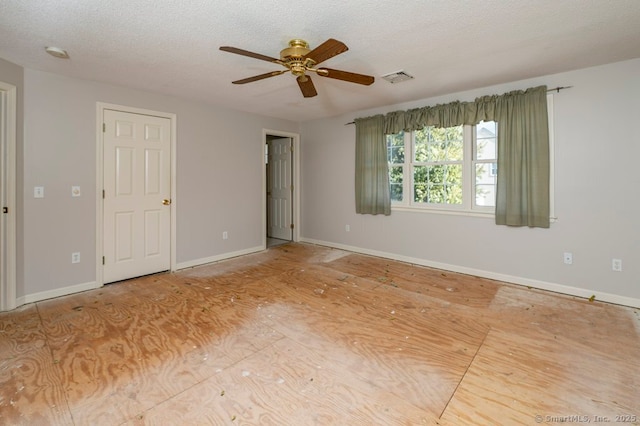 spare room featuring a textured ceiling, ceiling fan, visible vents, and baseboards