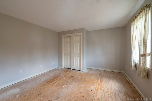 interior space featuring light wood finished floors, a textured ceiling, baseboards, and a closet