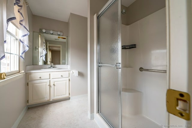 bathroom with a stall shower, vanity, and baseboards