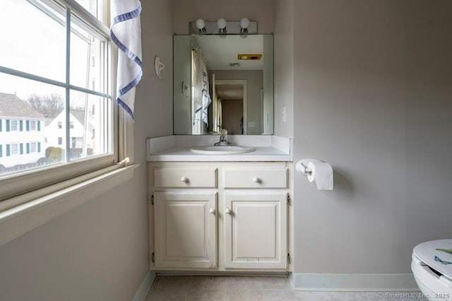 bathroom featuring toilet, vanity, and baseboards