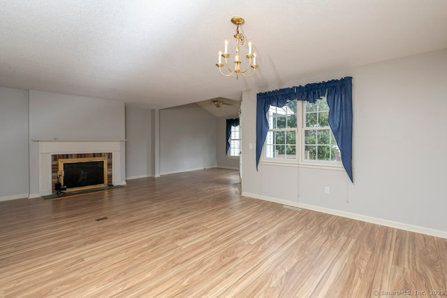 unfurnished living room with a notable chandelier, a textured ceiling, a fireplace with flush hearth, and light wood-style floors