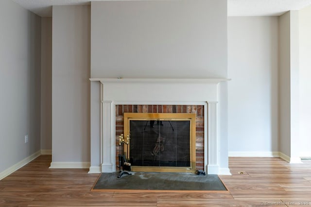 room details featuring a fireplace, baseboards, and wood finished floors