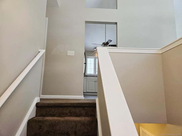 staircase with baseboards and a ceiling fan