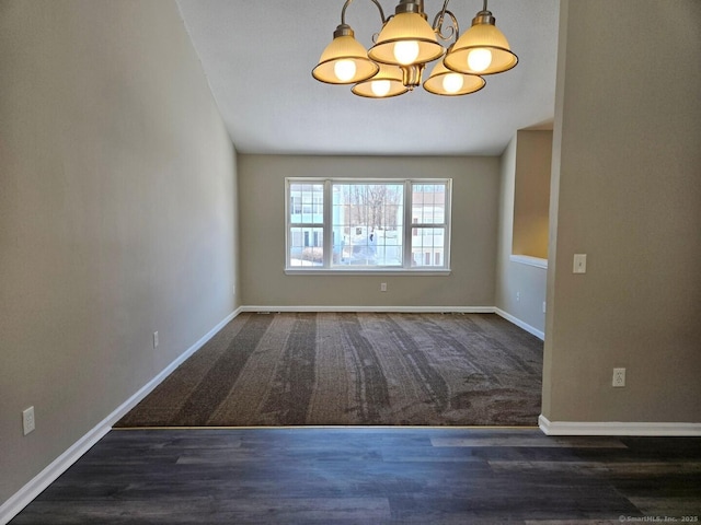 spare room featuring baseboards, a chandelier, and wood finished floors