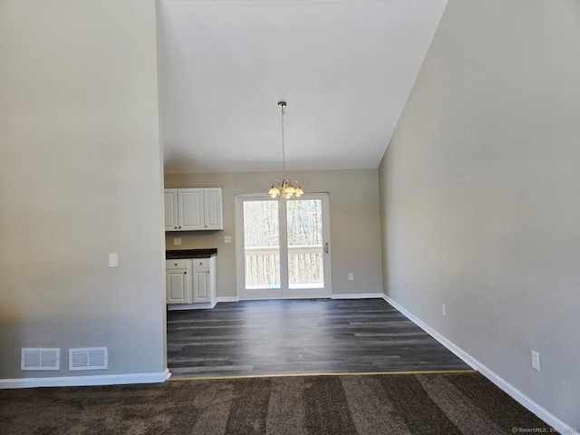 unfurnished dining area featuring baseboards, visible vents, and an inviting chandelier