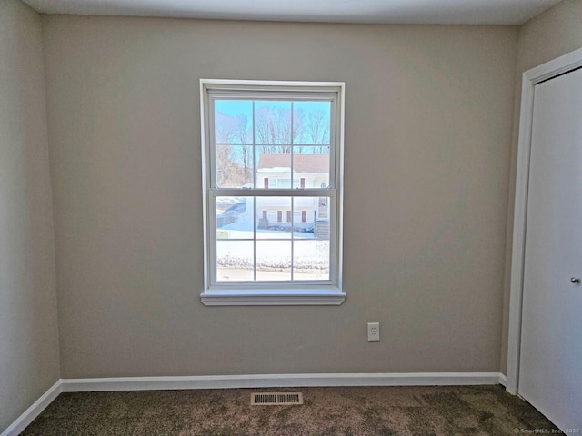 carpeted empty room featuring a healthy amount of sunlight, baseboards, and visible vents