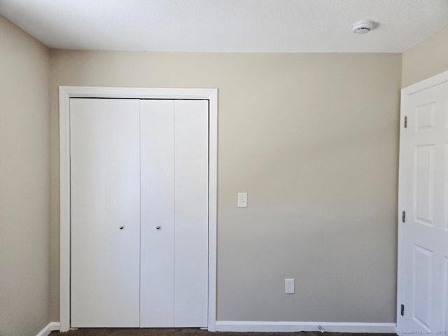 unfurnished bedroom with a closet and baseboards